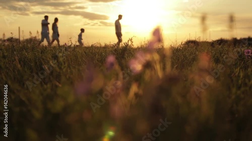 The family walks across the field amid a beautiful sunset, the child runs to his father