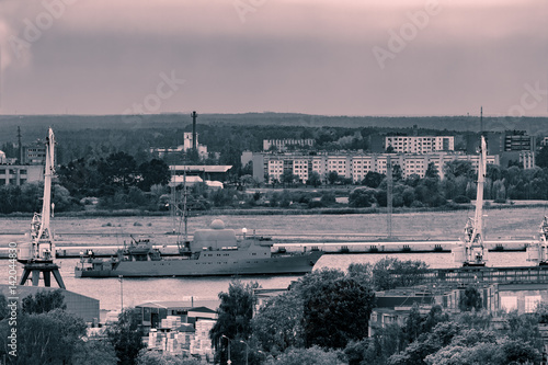 Military ship sailing past the cargo port in Riga  Latvia