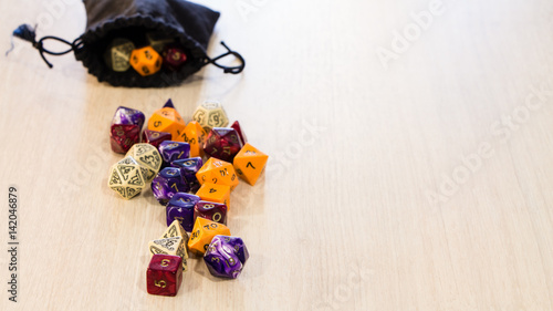 Colorful roleplaying dice scattered on a table with a linen dice pouch