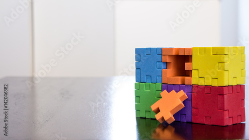 Colorful cube puzzle missing a piece on a table with reflection