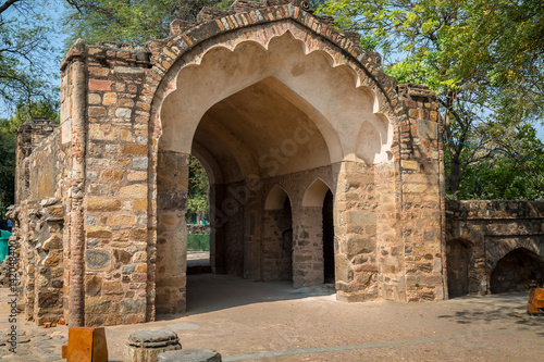 Ancient stone brick gate and ruins at the Qutb Minar site in Delhi, India. Qutb Minar, along with the ancient medieval monuments form the Qutb complex, which is a UNESCO World Heritage Site.