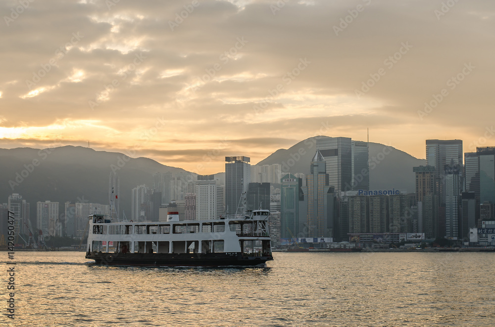 Star ferry in Victoria Harbor and HK skyline at sunrise. View from Kowloon on Hong Kong Island . Star ferry in Victoria Harbor and HK skyline at sunrise. View from Kowloon on Hong Kong Island .