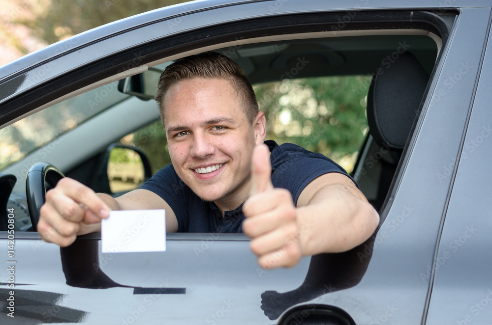 Happy young man showing off his drivers licence