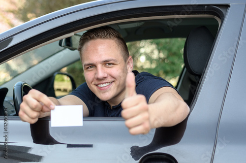 Happy young man showing off his drivers licence © michaelheim