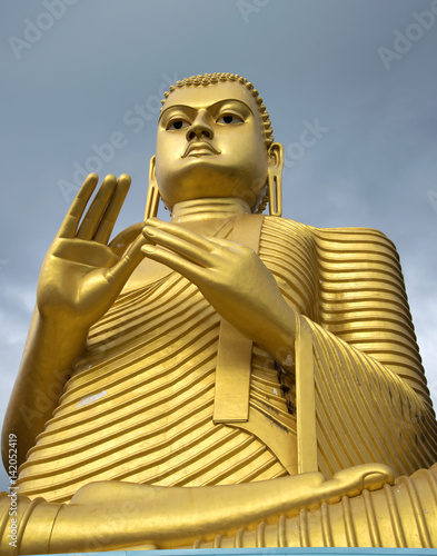 Sculpture of the seated Buddha on top of the Golden Temple close-up. Dambulla, Sri Lanka