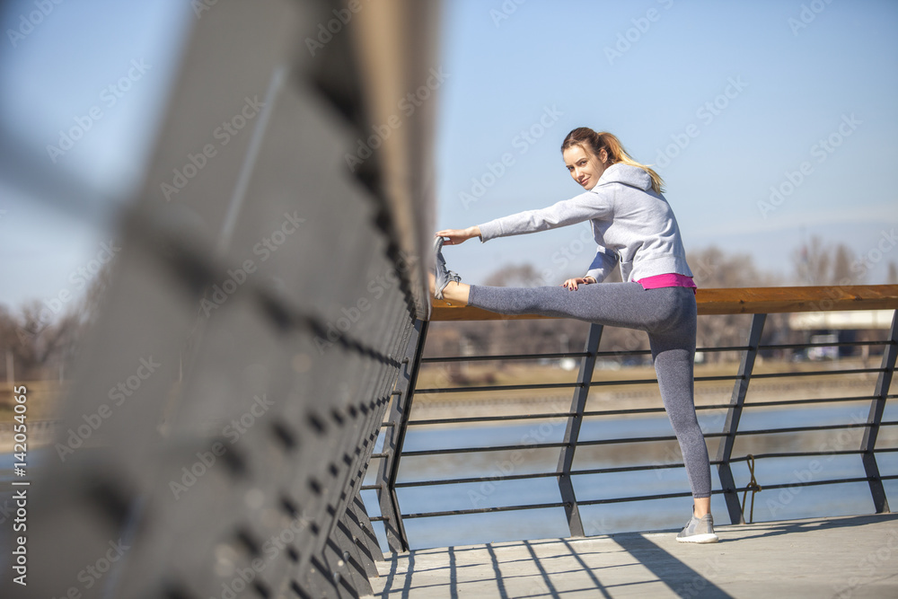 Young woman on recreation and jogging.Warm up and stretch muscles before exercise by the river Young woman on recreation and jogging.Warm up and stretch muscles before exercise by the river