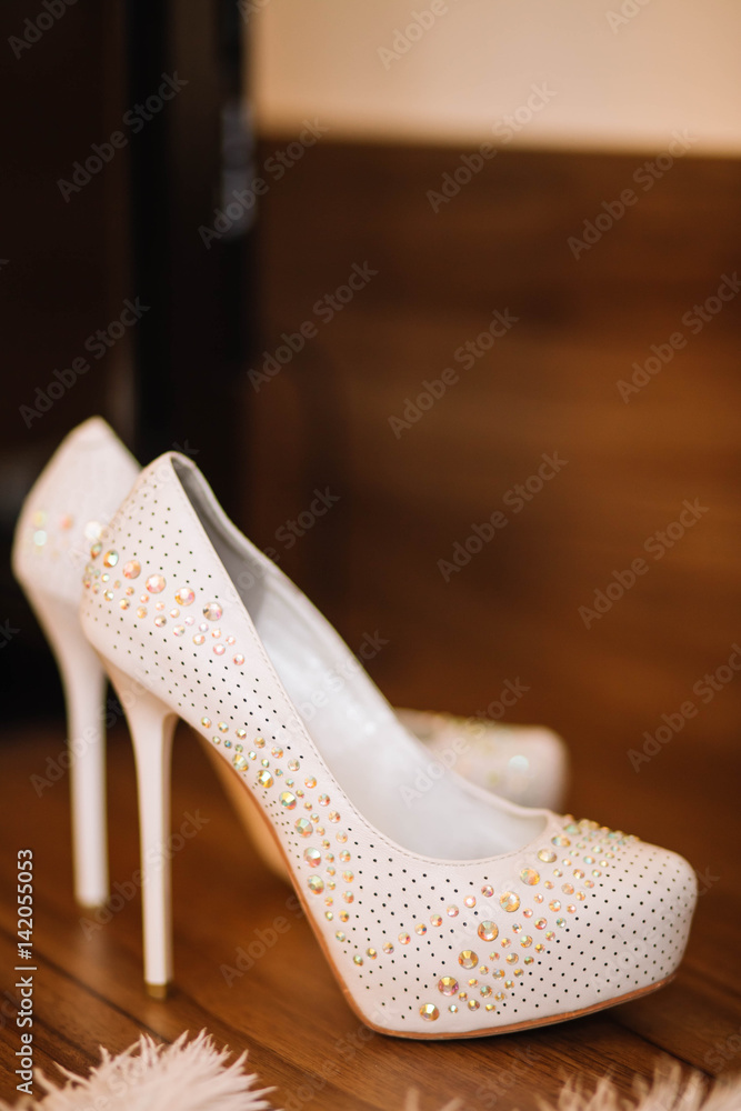 Obraz premium white wedding shoes with shiny rhinestones on a brown wooden background