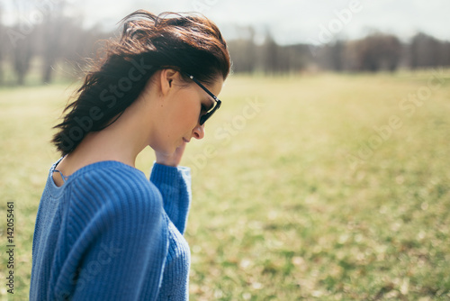 Back side view portrait of beautiful young brunette woman with the wind blowing hair on nature background. Attractive girl with sunglasses in park. Lifestyle concept. Cover idea concept.