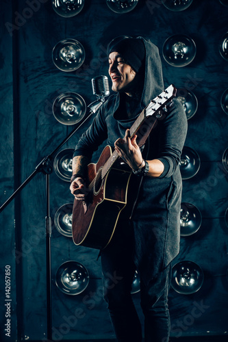 Silhouette of guitar player on stage. Dark background, smoke, spotlights