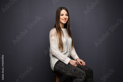 Portrait of pretty young woman with long hair in white shirt sitting on stool chair photo
