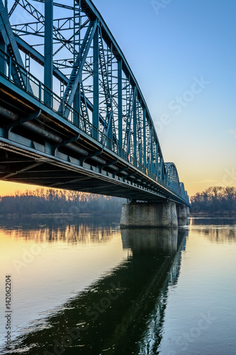 Fototapeta Naklejka Na Ścianę i Meble -  Jozef Pilsudski road bridge reflected in Vistula river in the morning. Torun, Poland. Europe.