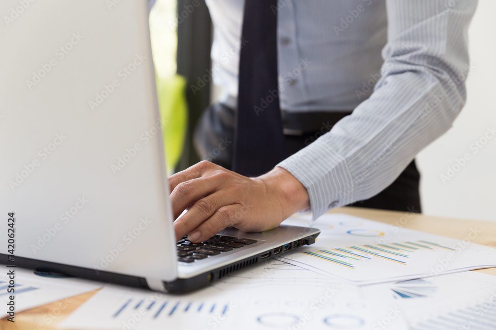 Businessman' s hands analyzing charts and graphs and typing on modern laptop computer. Businessman' s hands analyzing charts and graphs and typing on modern laptop computer.
