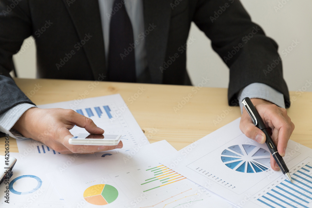 Businessman analyzing charts and graphs with smartphone. Businessman analyzing charts and graphs with smartphone.