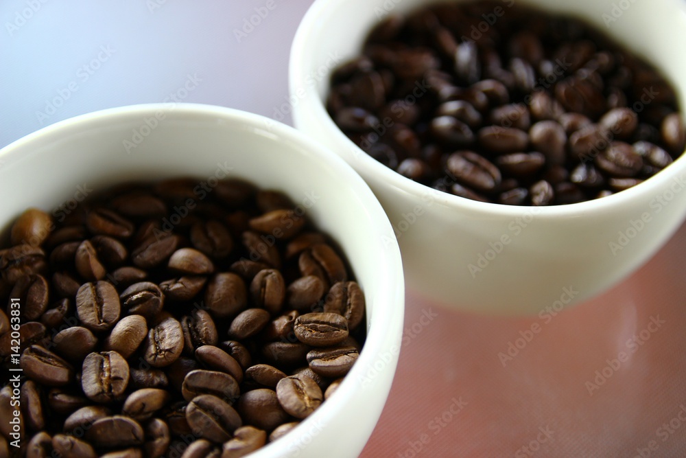 Closeup of roasted coffee beans in small white cups Closeup of roasted coffee beans in small white cups