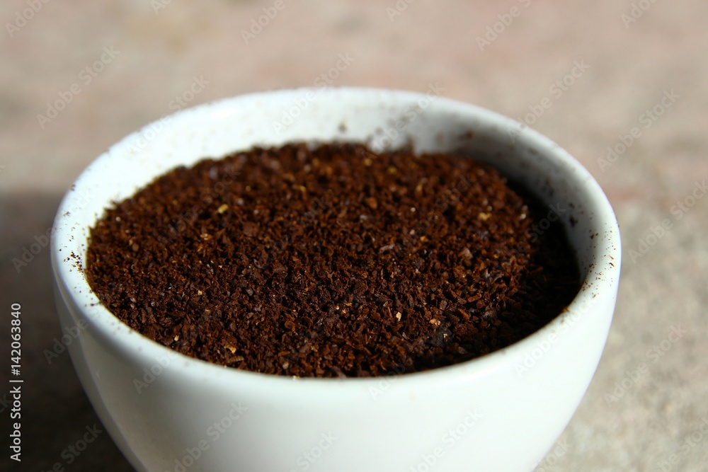 Closeup of grinded coffee beans in a small white cup Closeup of grinded coffee beans in a small white cup