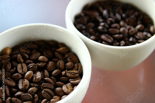 Closeup of roasted coffee beans in small white cups