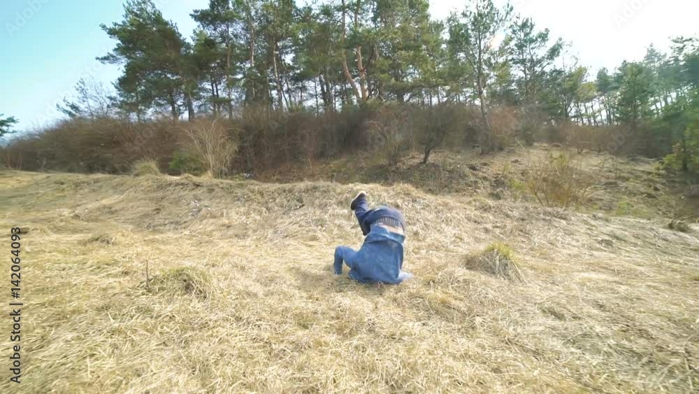 Young stunt shows hard tricks of parkour on the nature. Slowly