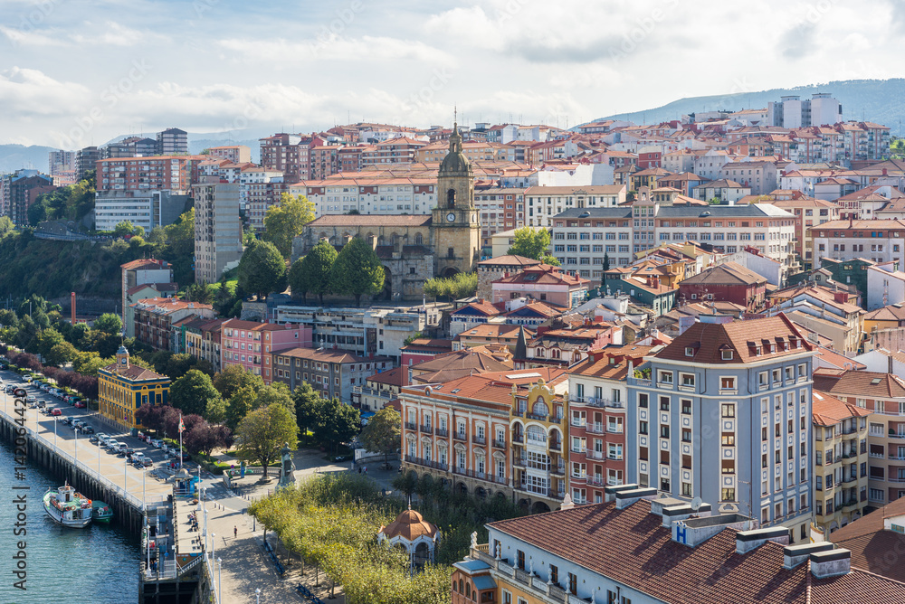 The town Portugalete to the right with the Basilica de Santa Maria de Portugalete, as seen from the bridge looking south. The Vizcaya Bridge is the worlds oldest transporter bridge, built in 1893