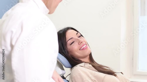 Close up of beautiful smiling woman talking with dentist while sitting in dental chair