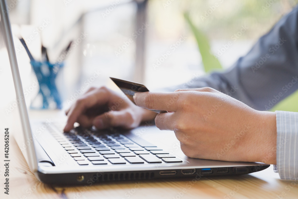 Businessman hand holding a Credit card intent to made a online payment with his computer laptop on his desk. Businessman hand holding a Credit card intent to made a online payment with his computer laptop on his desk.