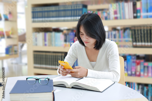 Asian student use smartphone in the library