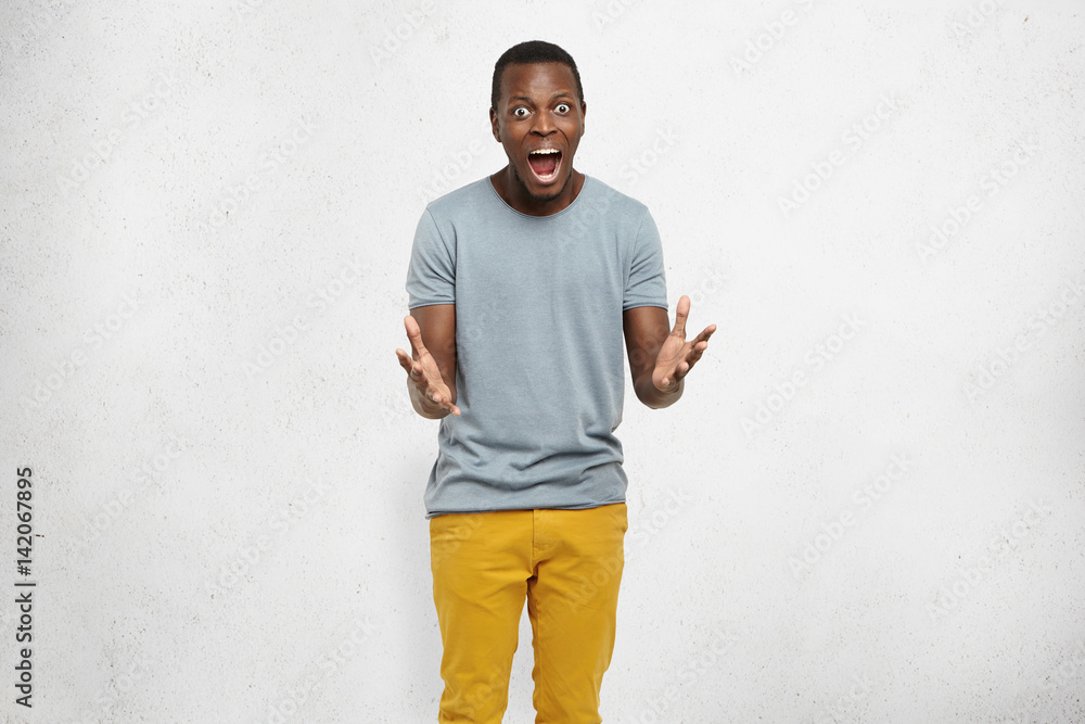 No way! Bug-eyed young dark-skinned male dressed casually having scared fearful look, screaming and gesturing actively with both hands, shocked with unexpected news. Human emotions and feelings No way! Bug-eyed young dark-skinned male dressed casually having scared fearful look, screaming and gesturing actively with both hands, shocked with unexpected news. Human emotions and feelings