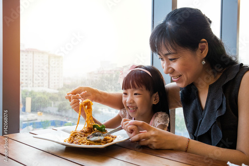 Asian Chinese mother and daughter eating spaghetti bolognese