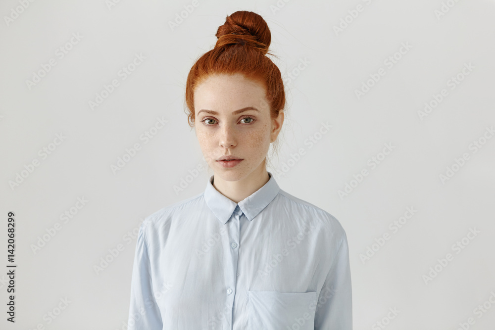 People and lifestyle. Attractive European student girl with freckles and  ginger hair in bun wearing formal shirt, ready for college, standing at  white wall with copy space for your advertisement Stock Photo |