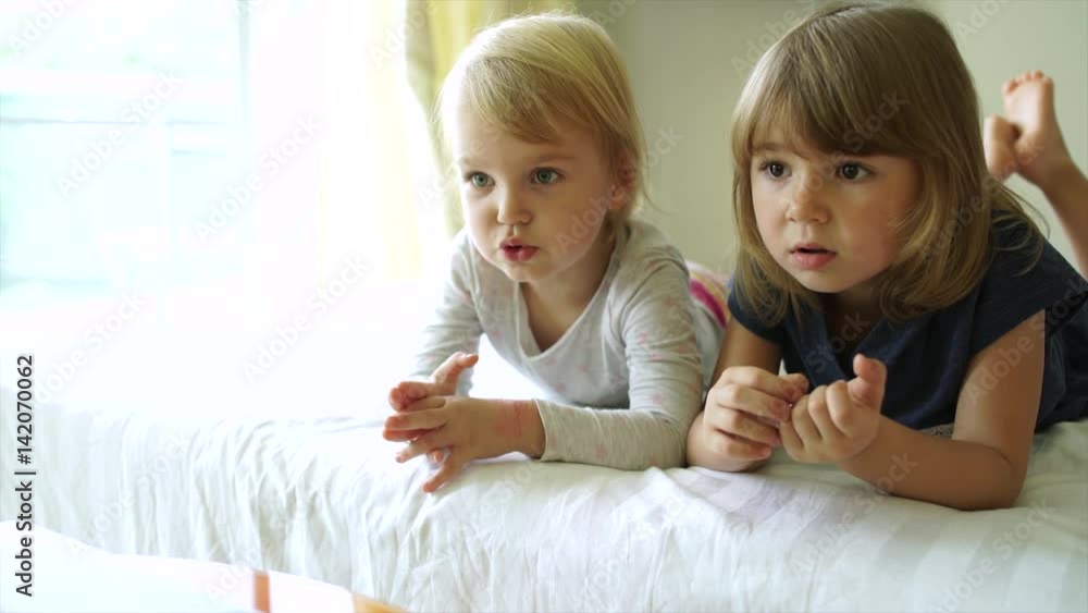 Two little sisters watching cartoons on the laptop with different emotions on faces 4K Two little sisters watching cartoons on the laptop with different emotions on faces 4K
