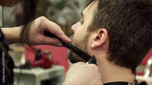 Hairdreser is cutting man's beard, closeup photo