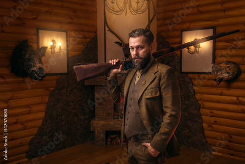 Canvas Print Hunter man with old gun against antique chest