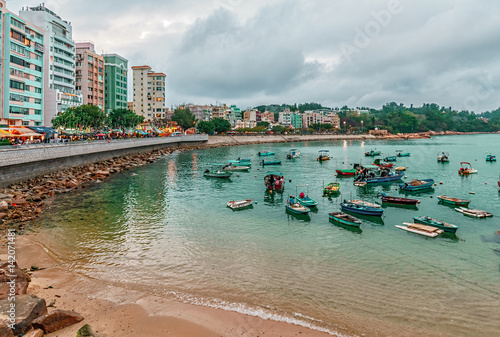 Hong Kong, China - January 30, 2016: Fishing boats rest in Stanley Bay by seashore on buildings background. Beautiful scenic landscape of Stanley waterfront in the evening