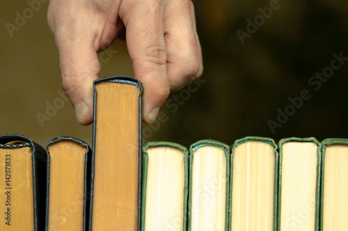 hand of the person pulls the book off the shelf in the library photo