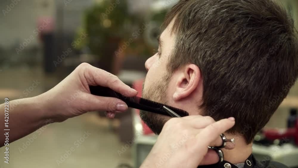 Hairdreser is cutting man's beard in salon, closeup Hairdreser is cutting man's beard in salon, closeup