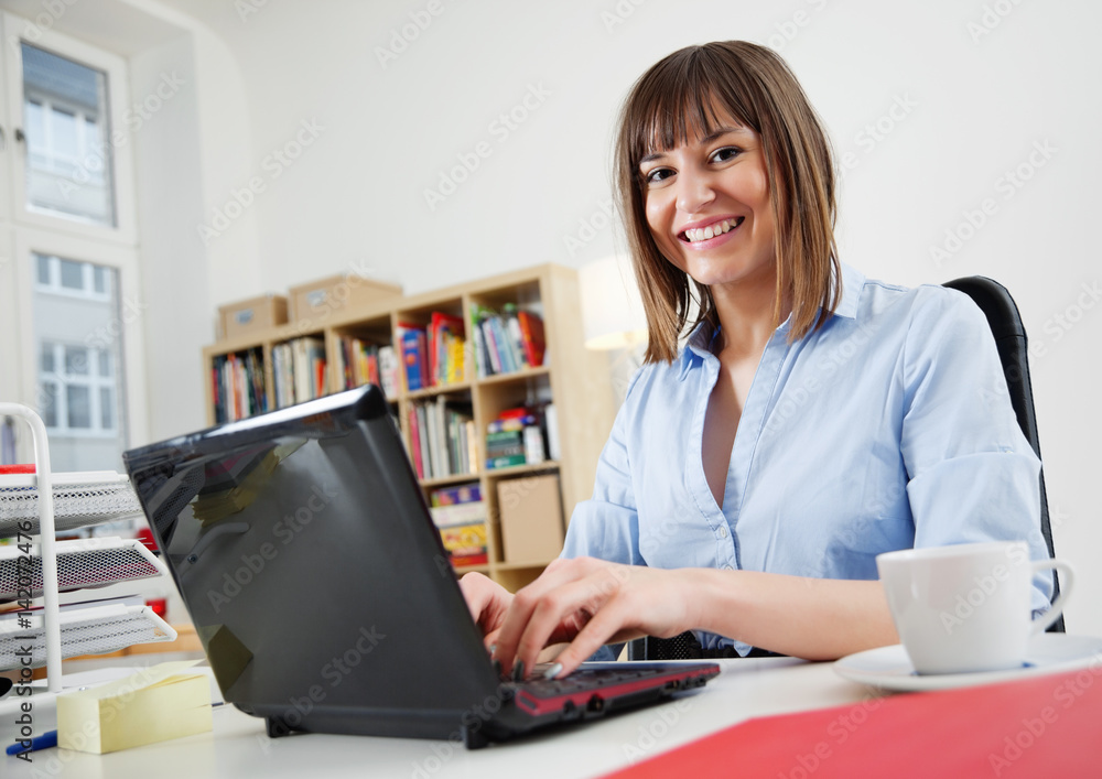 Beautiful young Woman in her Home Office working on a small Laptop Netbook Beautiful young Woman in her Home Office working on a small Laptop Netbook