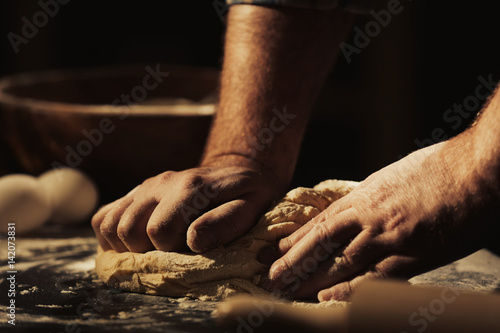 Hands of man kneading dough in kitchen, closeup © Africa Studio