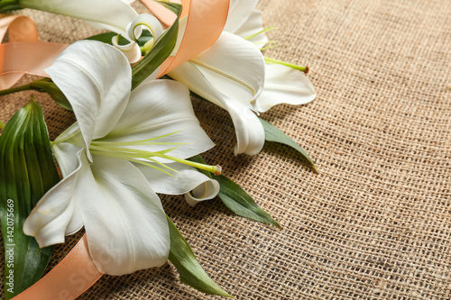 Fototapeta Naklejka Na Ścianę i Meble -  Beautiful lilies and ribbon on fabric background