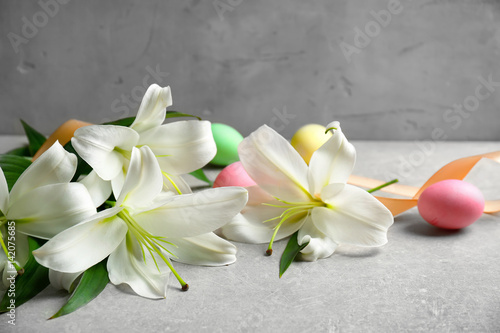Fototapeta Naklejka Na Ścianę i Meble -  Beautiful lilies, eggs and ribbon on gray table