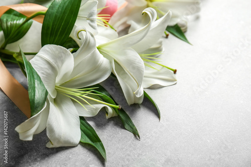 Fototapeta Naklejka Na Ścianę i Meble -  Beautiful lilies, eggs and ribbon on gray background