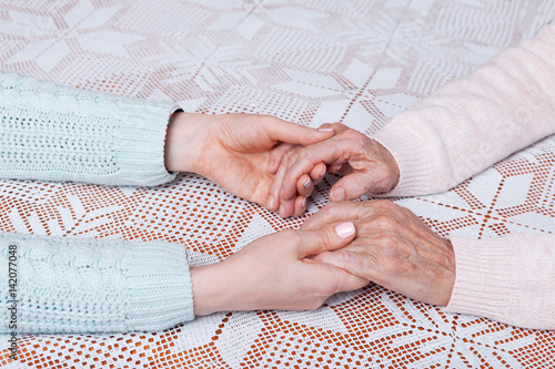 A care is at home of elderly. Holding hands closeup