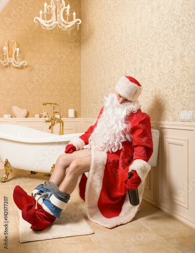 Drunk Father Christmas sitting on the toilet