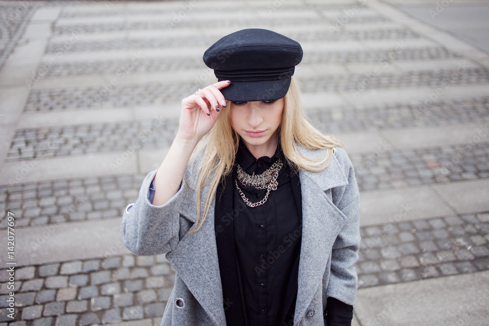 Young, hip and attractive blonde walking around the city, girl in a stylish hat and a gray coat. Pedestrian crossing