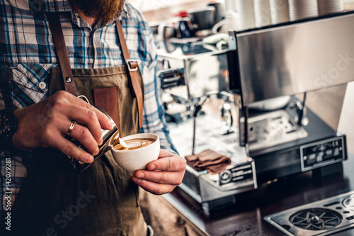 A man preparing cappuccino in a coffee machine.