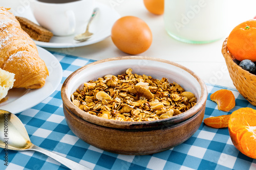 Healthy food for breakfast on a white wooden table. Oatmeal granola with nuts, coffee, croissants, eggs, milk and fruits for delicious healthy meal. Close-up. © Maxim Khytra