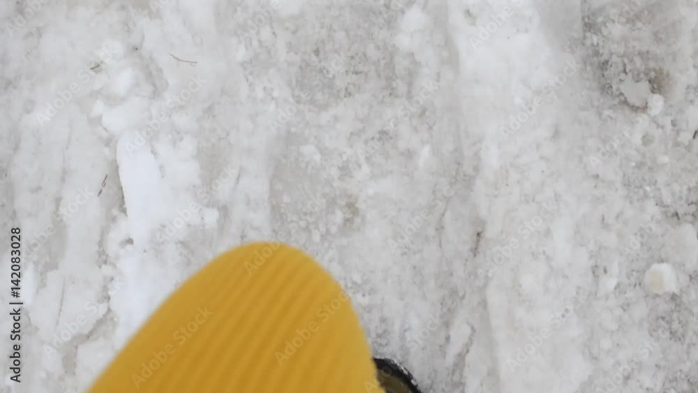 Legs in colored boots and a yellow knit pants walking in the snow, top view, to go, the top view of the feet Legs in colored boots and a yellow knit pants walking in the snow, top view, to go, the top view of the feet