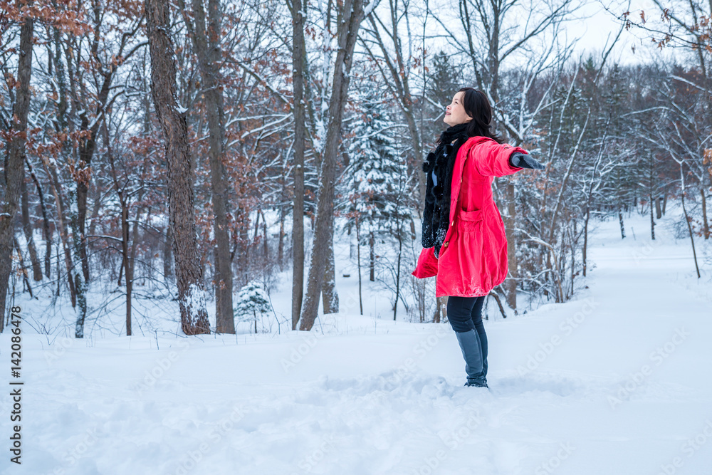 A young woman with a red jacket is playing in snow