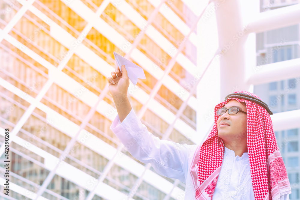 Fototapeta premium Arab businessman with paper airplane. Cheerful Arab businessman dreaming a good life.