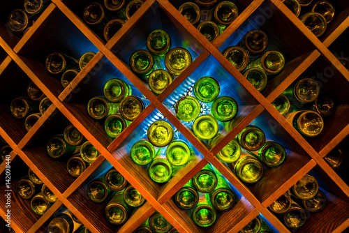 Empty green wine bottles on wooden shelves