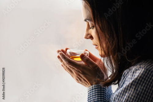 Yound dark haired woman holding glass of Fresh herbal tea