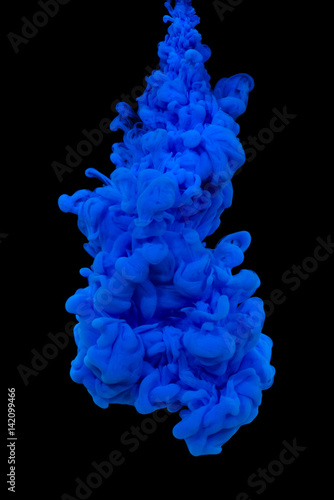 Explosion of blue acrylic paint in water on black background.